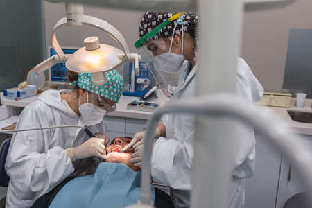 Female dentist with a patient in her office. Patient with open mouth and woman dentist working. dental health concept.の写真素材