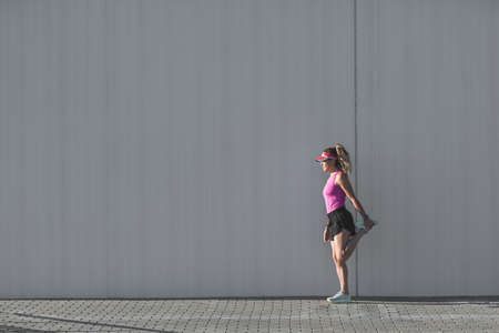 Woman stretching her legs before a run on a city street. Preparation for running workoutの写真素材