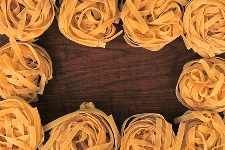 Yellow tagliatelle italian pasta border on wooden backgroundの写真素材