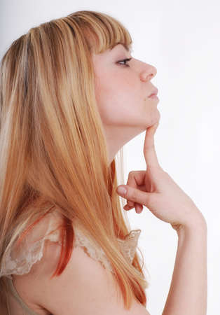 Studio portrait of young pensive woman in profile. Beautiful blond touching by finger her chin.の写真素材