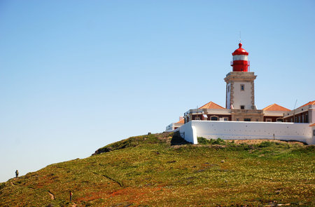 Horisontal image of red lighthouse, blue sky and  green hills on Cape Roca (Portugal).Composition...