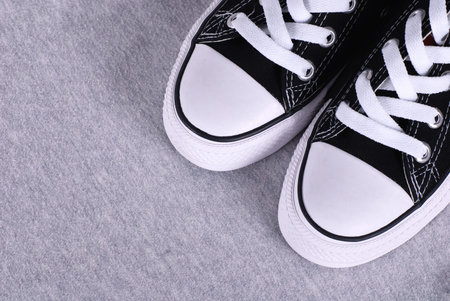 A pair of black canvas sneakers on grey textile background with copyspace