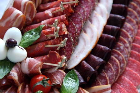 Assortment of delicatessen cold meat, salami, ham and bacon with tomato cherry. Selective focusの写真素材