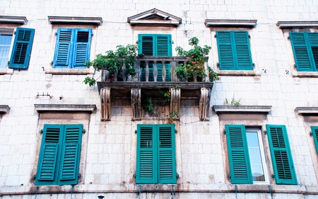 Ancient wall of mediterranean medieval house with shatters, windows, balcony (Kotor, Montenegro).の写真素材