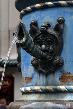 Close-up detail of medieval fountain with face blowing shell horns and stream water in Lucerne, Switzerland. の写真素材