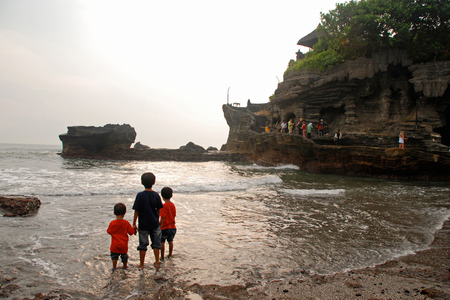 INDONESIA, BALI - JANUARY 04,2011:Tanah Lot temple, silhouette of three boys and sea waves in sunset on Bali island, Indonesiaのeditorial素材
