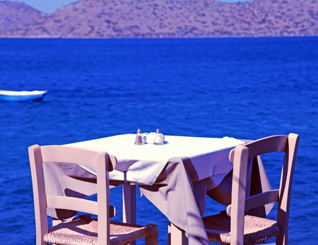 traditional greek outdoor restaurant with Mediterranean sea view(Crete, Greece). Toned imageの写真素材