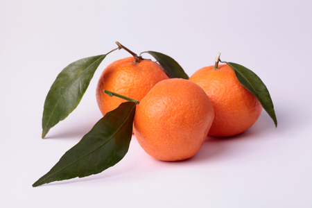 three tangerines with leaves on white backgroundの写真素材
