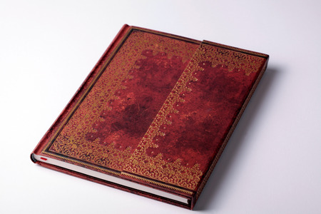 brown leather old note book with gold ornament on white backgroundの写真素材