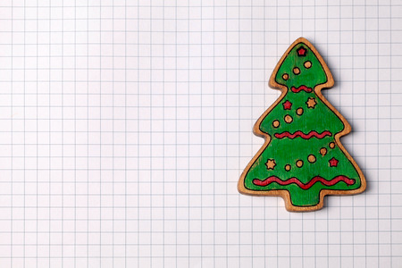 Handmade painting wood christmas tree decoration on white squared paper background with copy spaceの写真素材