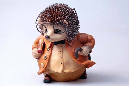 old shabby toy hedgehog with book, glasses and orange coatの写真素材