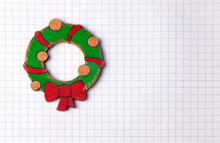 Handmade painting wood christmas decoration on white squared paper background with copy space