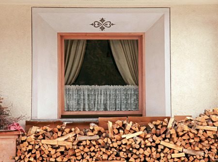 Window and pile of firewood stacked up in front of house in the Alps, Italyのeditorial素材