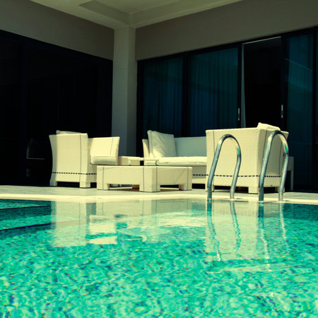 Beautiful swimming pool with white outdoor furniture on modern luxury resort, square toned image,...