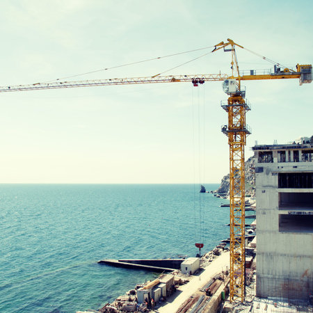 Tall yellow crane on construction of the new expensive apartment building on the sea...