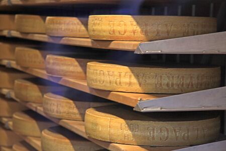 GRUYERES, SWITZERLAND - MAY 8, 2013: Famous Swiss cheese matures at the shelfs of cheese dairy in Gruyeres, Switzerland. Selective focusのeditorial素材