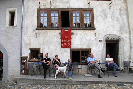GRUYERES, SWITZERLAND - MAY 08, 2013: People in traditional cafe in the swiss village Gruyeres, Switzerland. The most popular Swiss dishes are fondue and raclette with Swiss Cheese called Gruyere.のeditorial素材