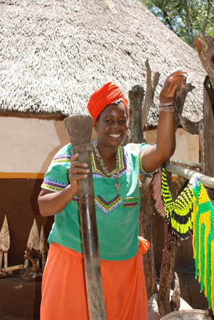 LESEDI,SOUTH AFRICA - JANUARY 1, 2008: Outdoor portrait of a beautiful black woman in Cultural village Lesedi, South Africa. She cooking traditional food and smiling .のeditorial素材