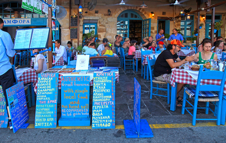 CRETE, GREECE - JULY 21, 2016: People sit in sidewalk street cafe in Chania waterfront on Crete island, Greece.のeditorial素材