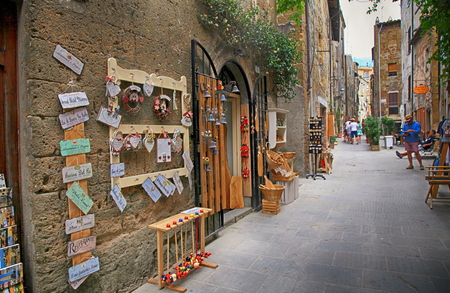 PITIGLIANO, ITALY - JULY 26, 2017: Narrow alley with gift shop in gorgeous etruscan and medieval town Pitigliano built of tuff stone, Tuscany, Italy. Called "little Jerusalem" for the historical presence of a Jewish community.のeditorial素材