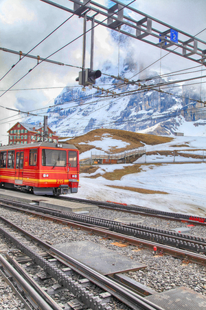 JUNGFRAU, SWITZERLAND - MAY 07, 2013: Railway station with red swiss train in Jungfrau, Switzerland. Train starts from Kleine Scheidegg and takes you directly to the Jungfraujoch-Top of Europe.のeditorial素材