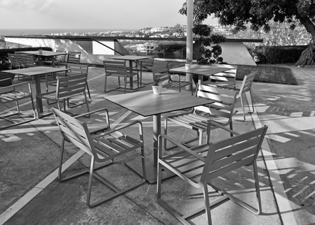 tables and chairs in outdoor cafe with sea view on sunset in Cyprus. Black and white imageの写真素材