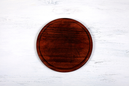 Brown wood cutting board on white wooden kitchen table. Empty round cutting board for cutting bread, pizza or steak, food background concept. Top viewの写真素材