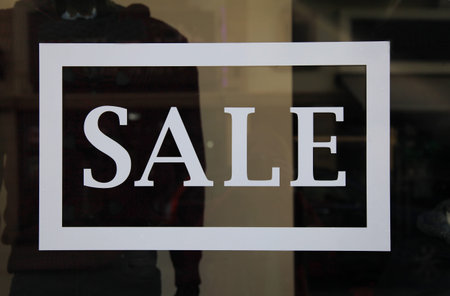 Sale sign on the shop window. Retail image of a white sale sign in a clothing store window 
