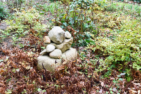 Large stones stacked as a marker in a garden in mid autumn with turning leaves.