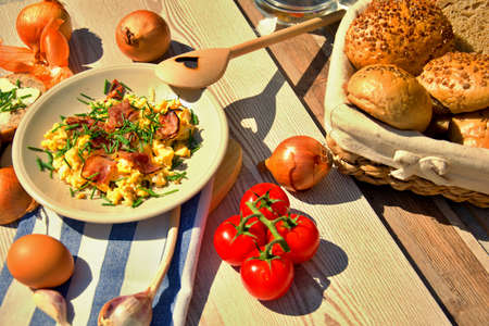 Fresh home-made breakfast eggs, onion and fried ham, set on a wooden tableの写真素材