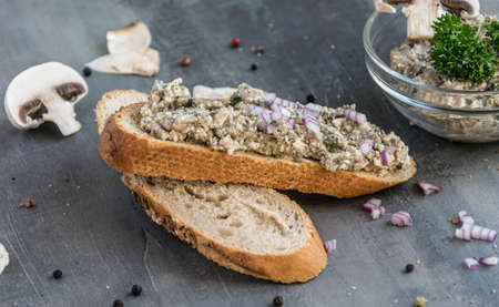 Fresh pastry with champignon spread on a gray background with whole colored pepper and pieces of mushroomsの写真素材