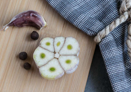 Fresh sliced ??garlic on a wooden board with colored pepper and bay leaf ready to flavorの写真素材