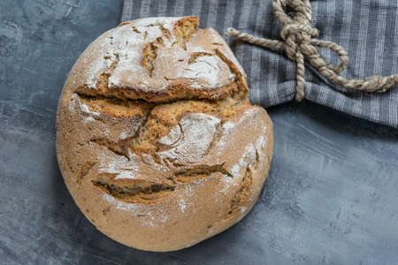 Fresh homemade caraway bread with sunflower seeds on a gray background with spilled flourの写真素材