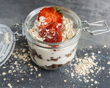 White yoghurt in a glass with chocolate balls, cia seeds, flakes and fruitの写真素材