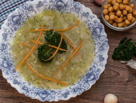 Zucchini soup with leeks and potatoes decorated with grated carrots and fresh parsleyの写真素材