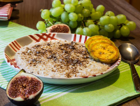 Delicious oatmeal with chocolate and pieces of fruit made of figs, bananas, grapes and cacti figsの写真素材