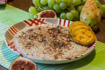 Delicious oatmeal with chocolate and pieces of fruit made of figs, bananas, grapes and cacti figsの写真素材