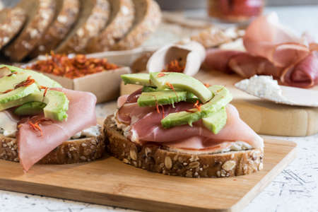 fresh bread with cottage cheese, prosciutto, avocado and saffronの写真素材