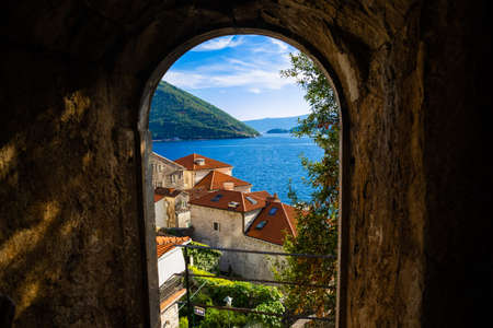 A trip to the tourist old town of the Adriatic coast Perast in Montenegro among the mountains and with beautiful old buildings with red tiles, there are many cafes in the city, narrow streets and clean air with seagulls and catsの写真素材