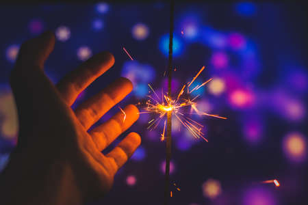 Photos on a bright blue purple background with sparklers festive lights holiday and Christmas and New Year on the desktop or banner on the websiteの写真素材