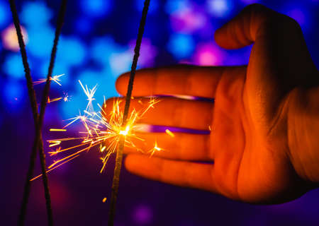 Photos on a bright blue purple background with sparklers festive lights holiday and Christmas and New Year on the desktop or banner on the websiteの写真素材