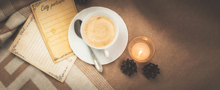 Cozy banner background with a cup of coffee, a postcard and books, a warm plaid and a place for your...