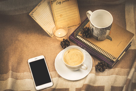 Cozy composition, winter comfort, background with a cup of hot coffee, with books, a smartphone and...