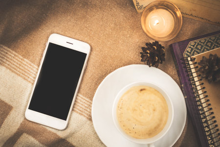 Home composition on plaid, cozy comfort with a cup of hot coffee and a smartphone, copy space photoの写真素材