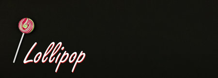 Round lollipop on black background, banner with stylized header or inscription, copy space, top view...