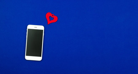 Concept of love message on smartphone, Valentine's day heart, new follower, banner design on flat blue background. High quality photoの写真素材