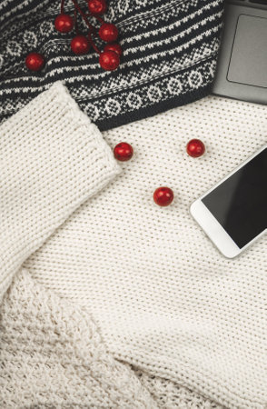 Simple winter workplace composition with cozy design for bloggers, knitted sweater, decoration and smartphone photoの写真素材