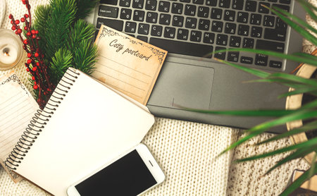 Cozy winter workplace and workspace, postcard, notepad and laptop on background of warm knitted sweater, flat lay composition photoの写真素材