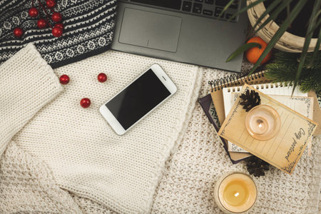 Winter and autumn workspace composition, flat lay mockup concept, smartphone, notebook, knitted sweater background with candle, blogger design photoの写真素材