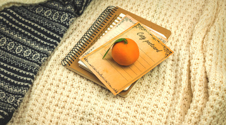 Winter cozy composition, books with tangerines on background of knitted warm sweaters, banner or mockup copy space photoの写真素材